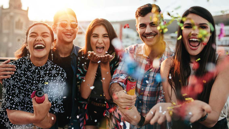 Group of friends outdoors celebrating and throwing confetti.